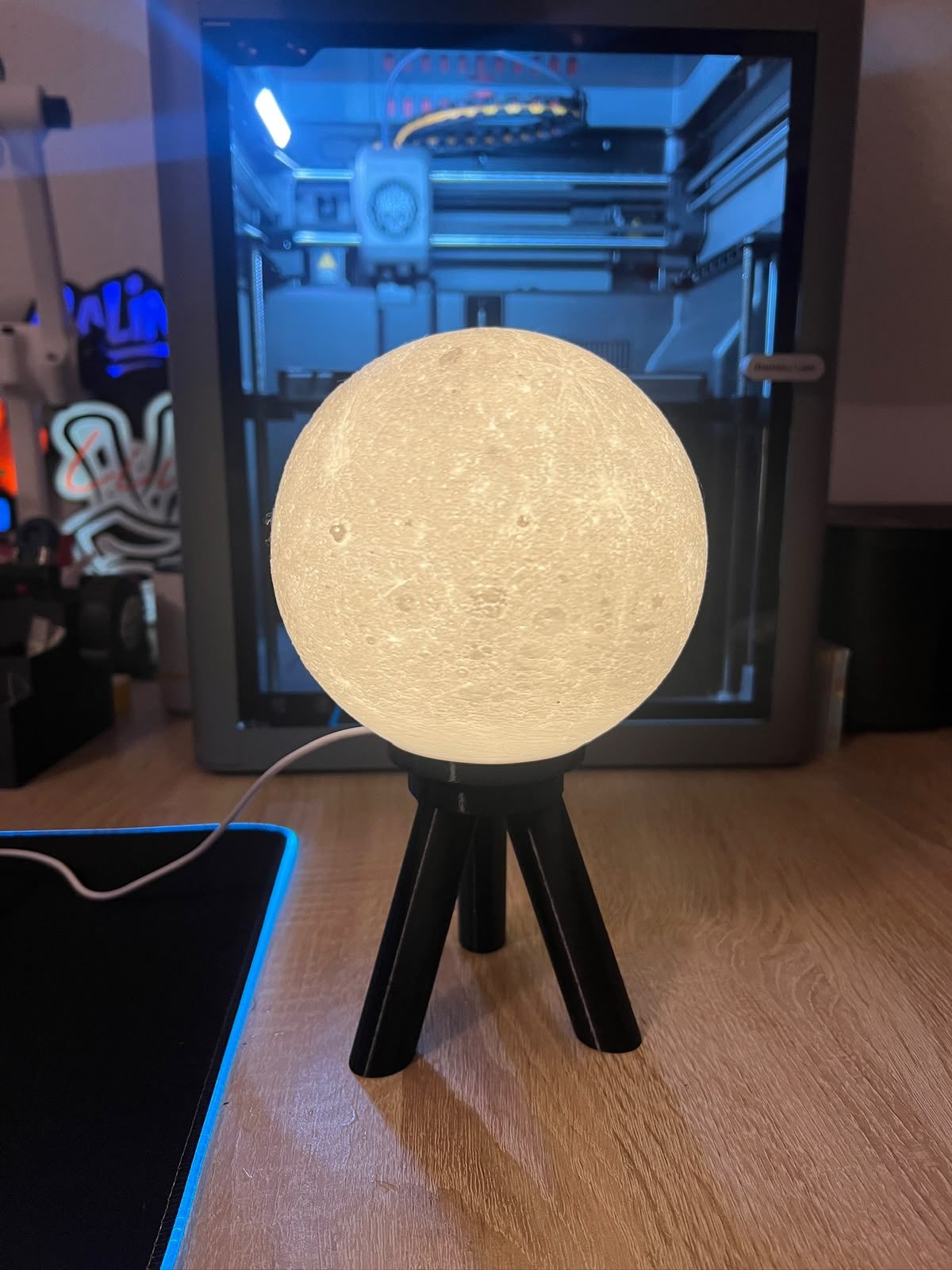 Lampa decorativa in forma de luna, asezata pe trepied